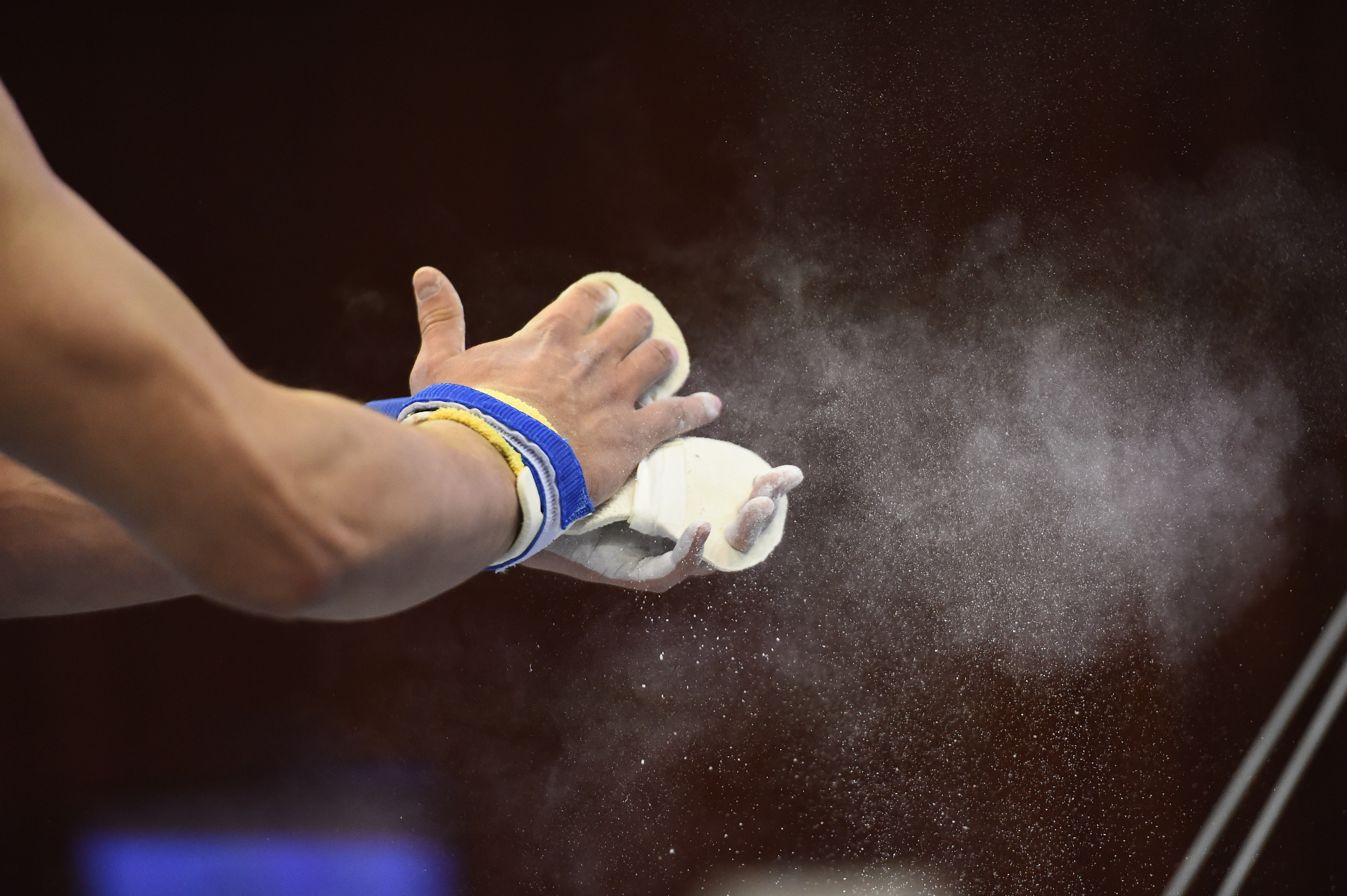 two hands slapping apart resin to help the gymnast with their flips