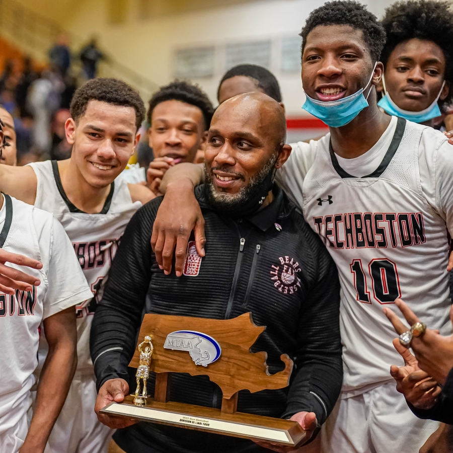 a happy coach holds a trophy surrounded by basketball players 